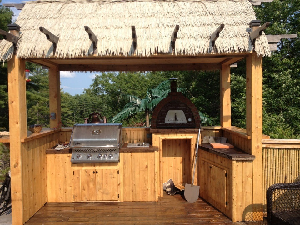 Wooden outdoor kitchen with grill and thatched canopy