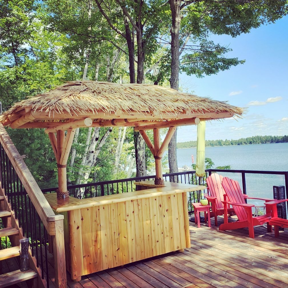 Thatched tiki bar on a lakeside deck with red chairs